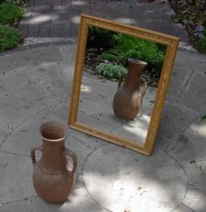 Marco ornamentado de un espejo antiguo reflejando una habitación con atmósfera satírica